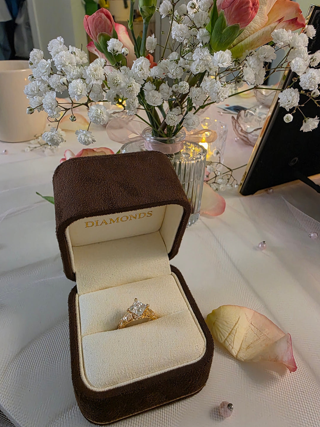 Hand-carved peony basket engagement ring in its box beside fresh flowers