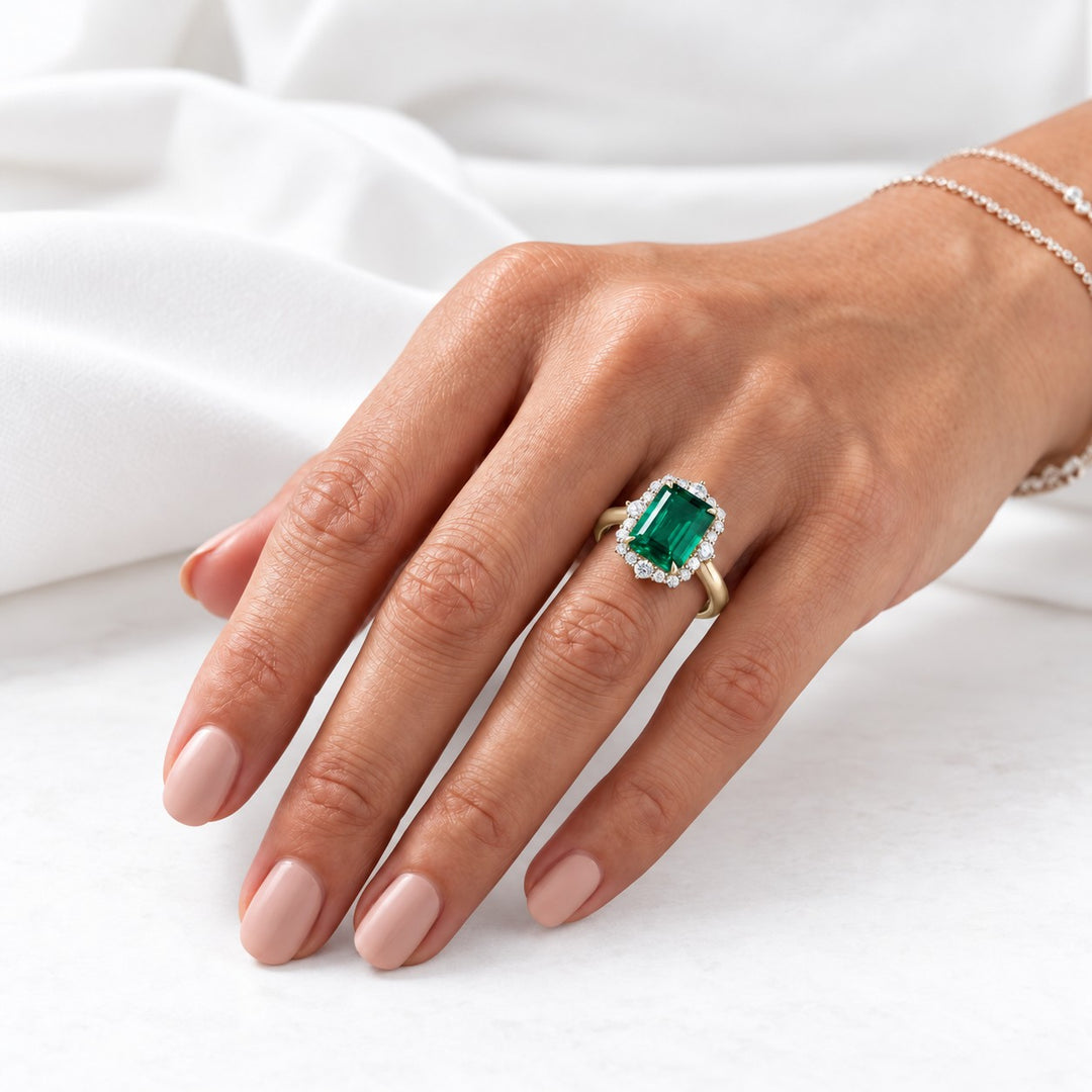 The Crown Halo — Diamond Halo Emerald Ring in 14K yellow gold, on the hand