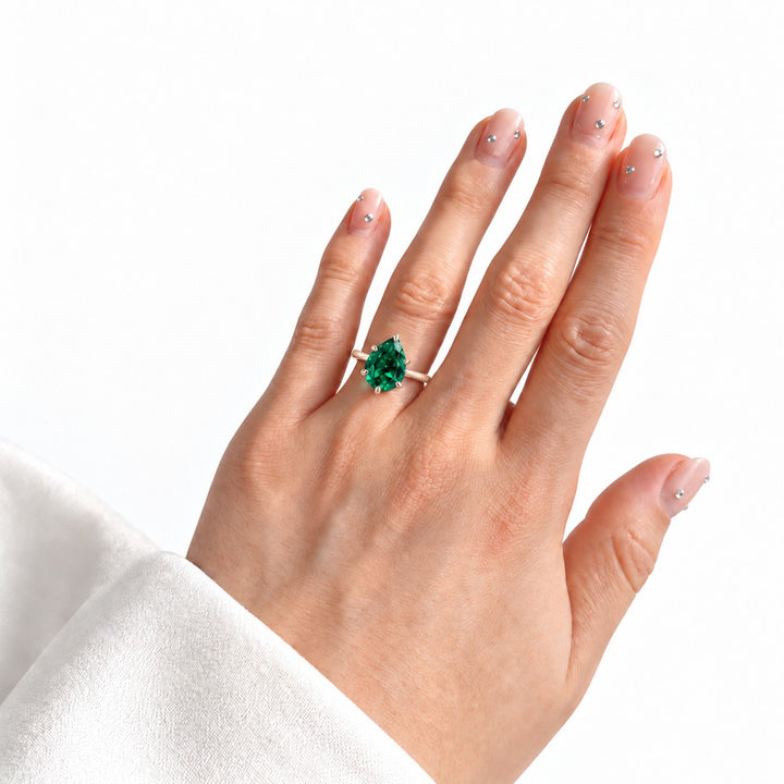 The Lotus Lace — Pear Emerald Ring (Petal Setting) in 14K rose gold, on the hand