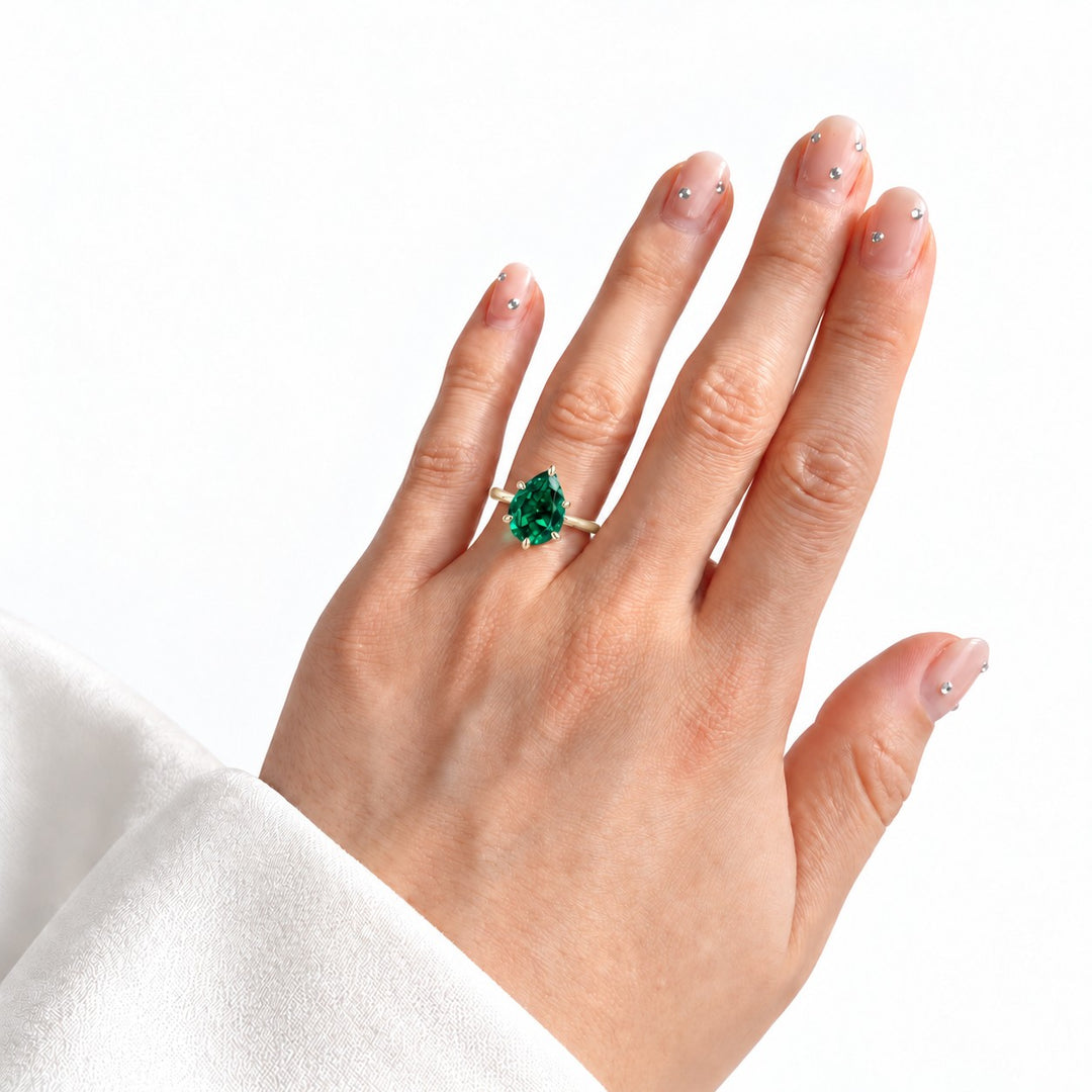 The Lotus Lace — Pear Emerald Ring (Petal Setting) in 14K yellow gold, on the hand