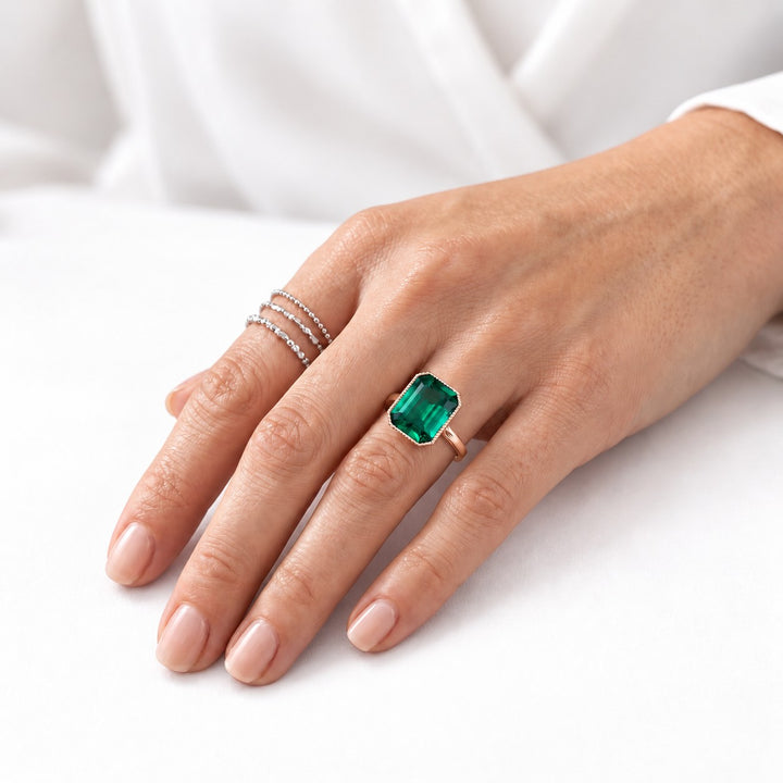 The Paragon — Milgrain Bezel Emerald Ring in 14K rose gold, on the hand