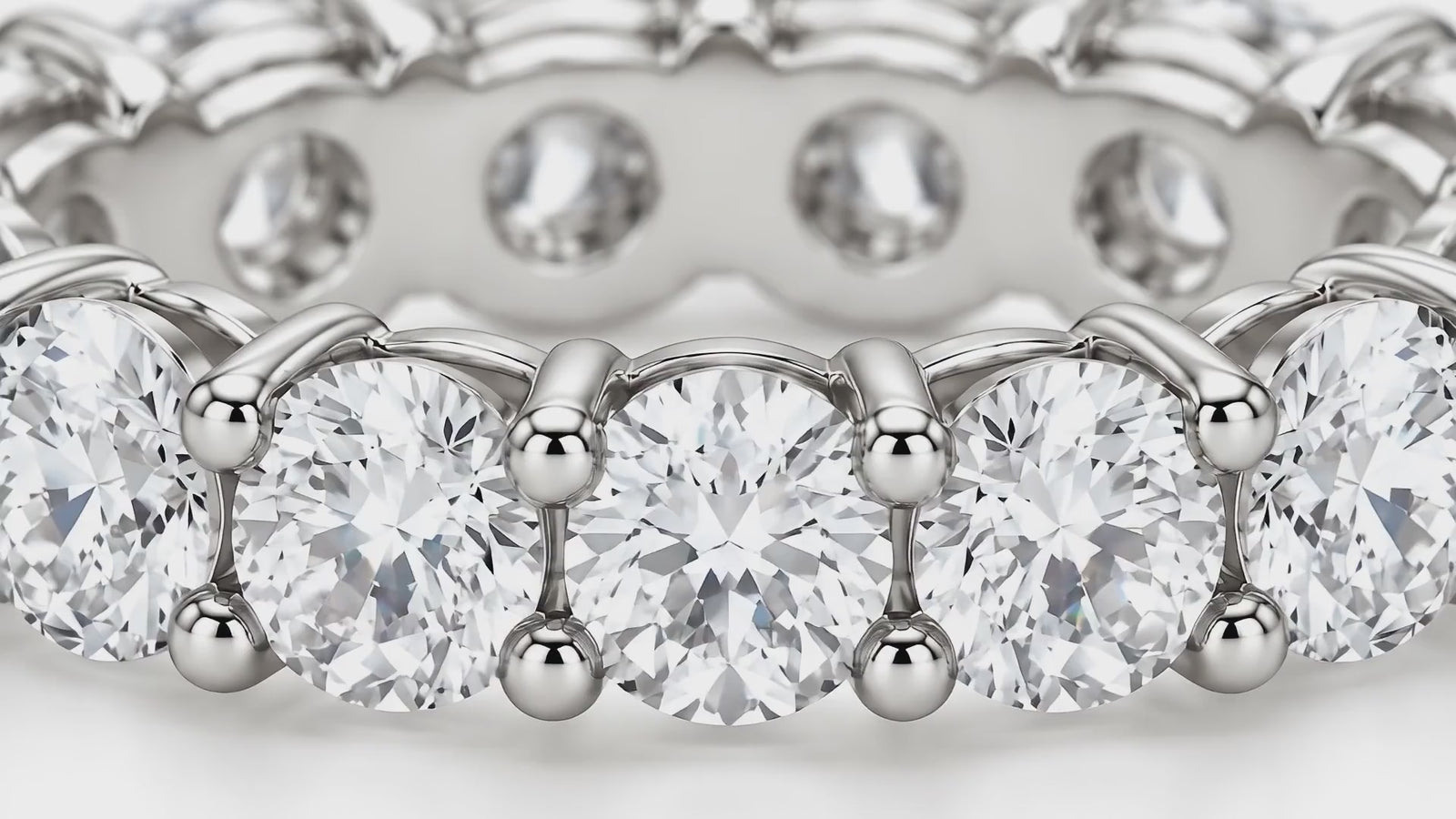 Macro of round diamonds on a white-gold eternity band catching the light