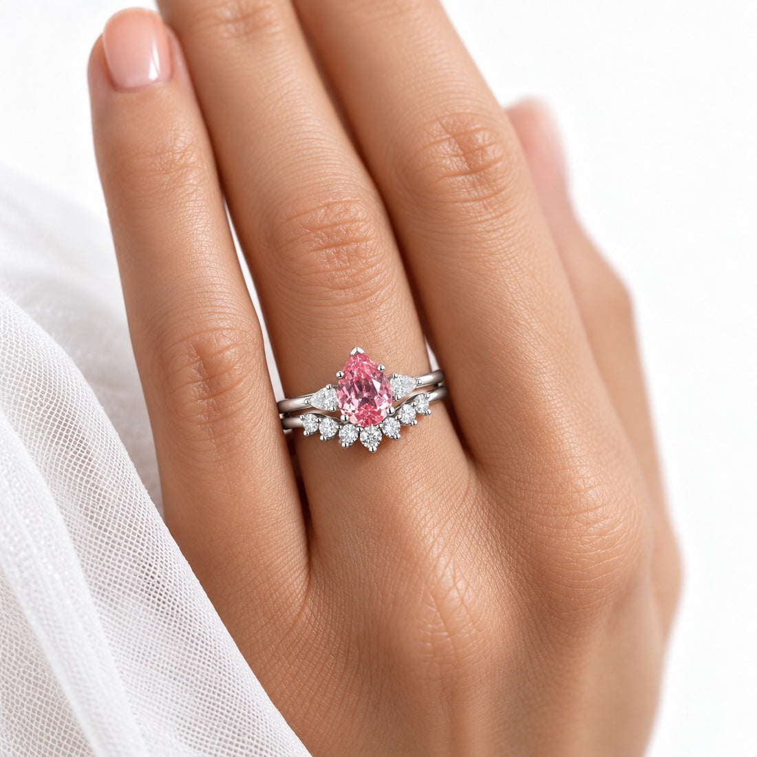 The Aubrey Set pink pear sapphire three-stone ring and diamond band in 14K white gold, worn on hand