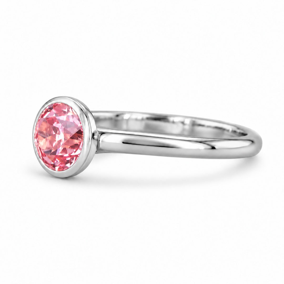 The Lune pink lab sapphire bezel solitaire ring in platinum, angled view