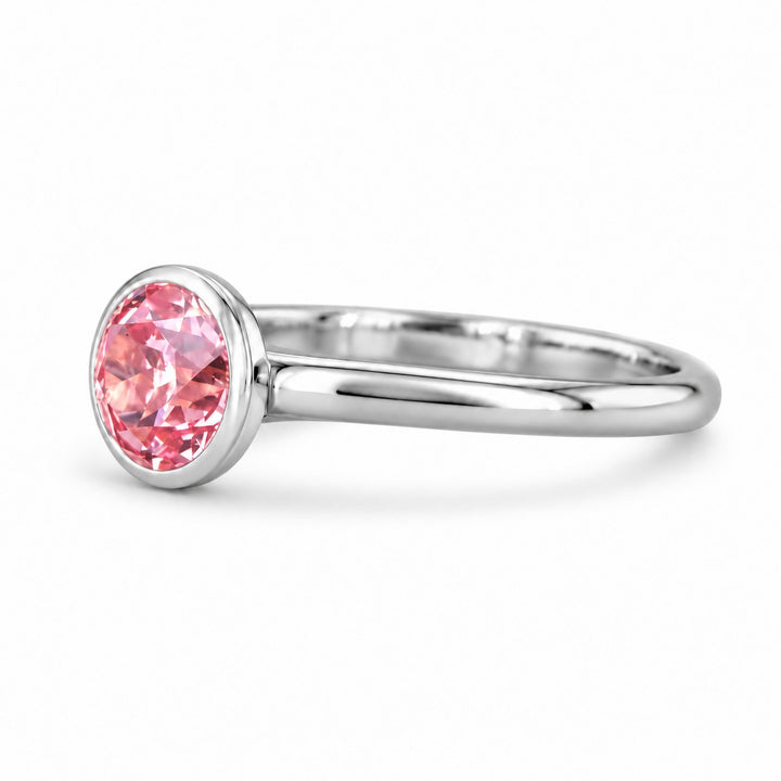 The Lune pink lab sapphire bezel solitaire ring in platinum, angled view