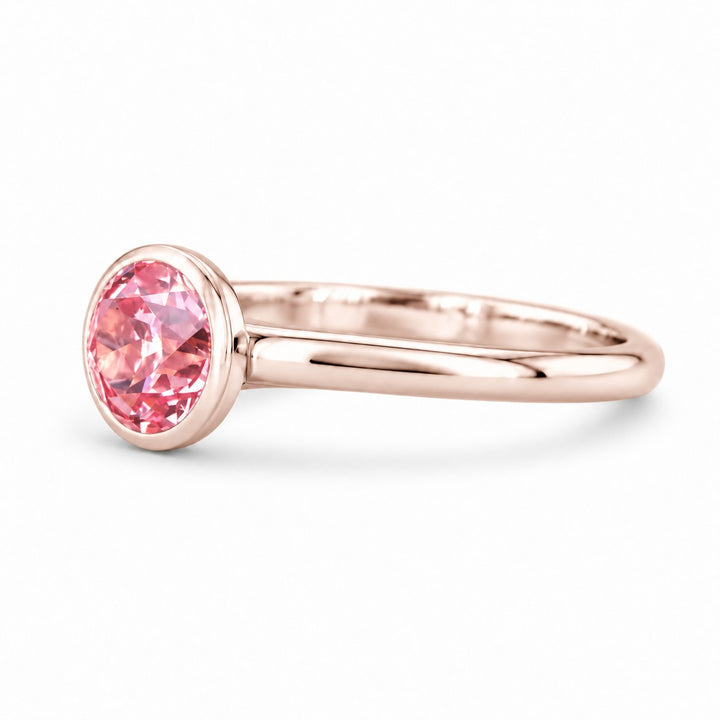 The Lune pink lab sapphire bezel solitaire ring in 14K rose gold, angled view