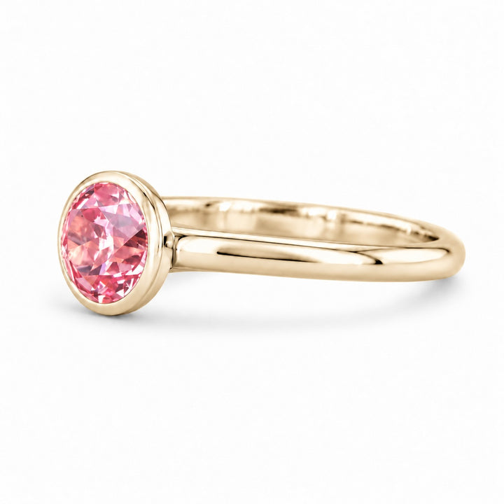 The Lune pink lab sapphire bezel solitaire ring in 14K yellow gold, angled view