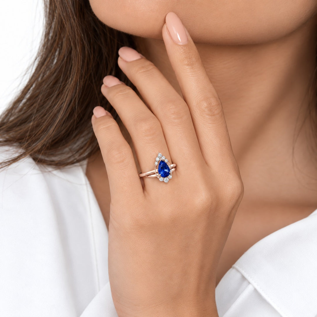 The Teardrop pear blue sapphire ring with diamond halo in 14K rose gold, worn on hand