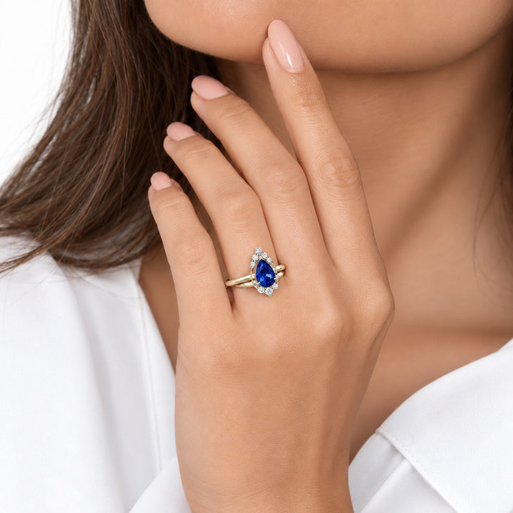 The Teardrop pear blue sapphire ring with diamond halo in 14K yellow gold, worn on hand