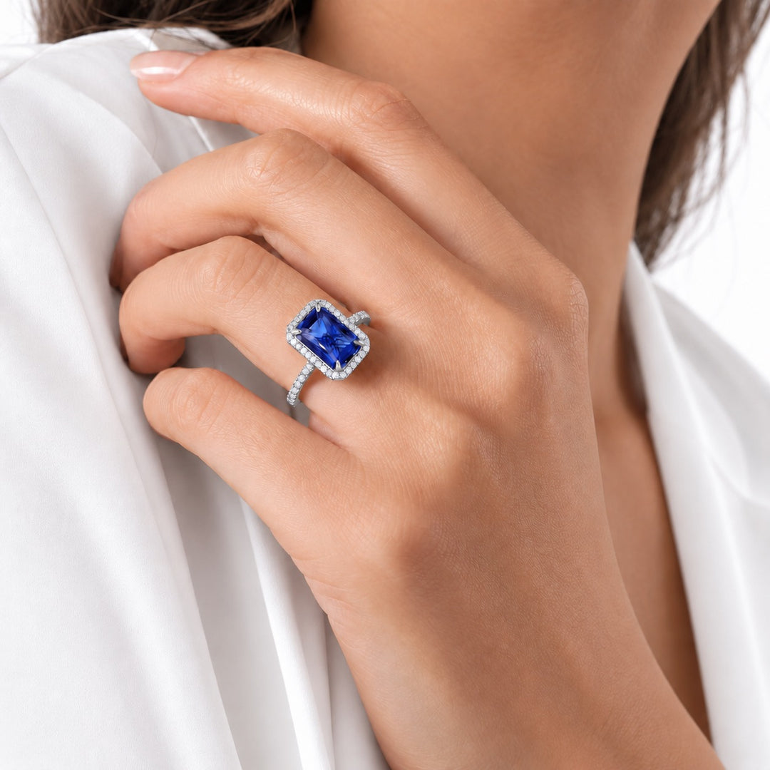 The Regalia emerald-cut lab sapphire halo ring in platinum, worn on hand