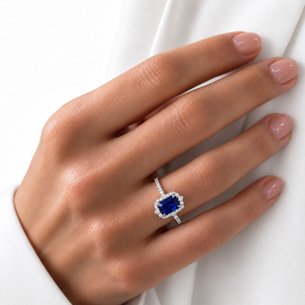 The Coronet emerald-cut lab sapphire vintage halo ring in 14K white gold, worn on hand