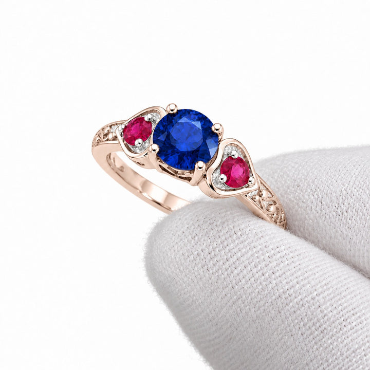 Sapphire and ruby three-stone ring with leaf band in 14K rose gold, angled view